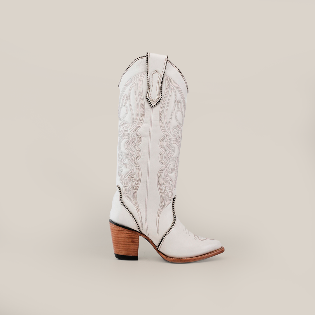 The Linda Studs Tall Shaft Frost White - J Toe cowboy boot features intricate artisanal craftsmanship, a tall shaft, and a brown stacked heel. Part of the Platinum Collection, its crafted from premium leather for timeless elegance against a plain gray background.