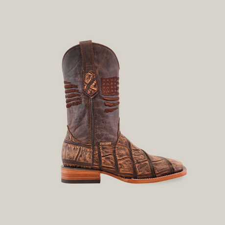 A single, handcrafted cowboy boot titled American Alligator Print Rustic Brown - Square Toe is made of brown leather with textured patterns and western-style stitching. It stands upright against a plain white background, highlighting its detailed craftsmanship and low wooden heel.