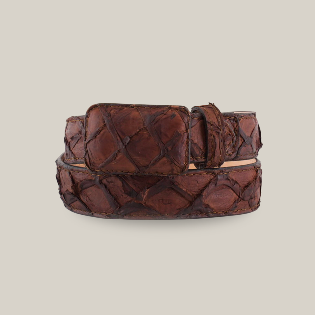 The Exotic Full Quilt Pirarucu Fish - Matte Brown Belt features a coiled design with a rectangular buckle and a textured pattern resembling woven strips. Its brown leather exudes rugged elegance with a glossy finish, set against a plain white background.