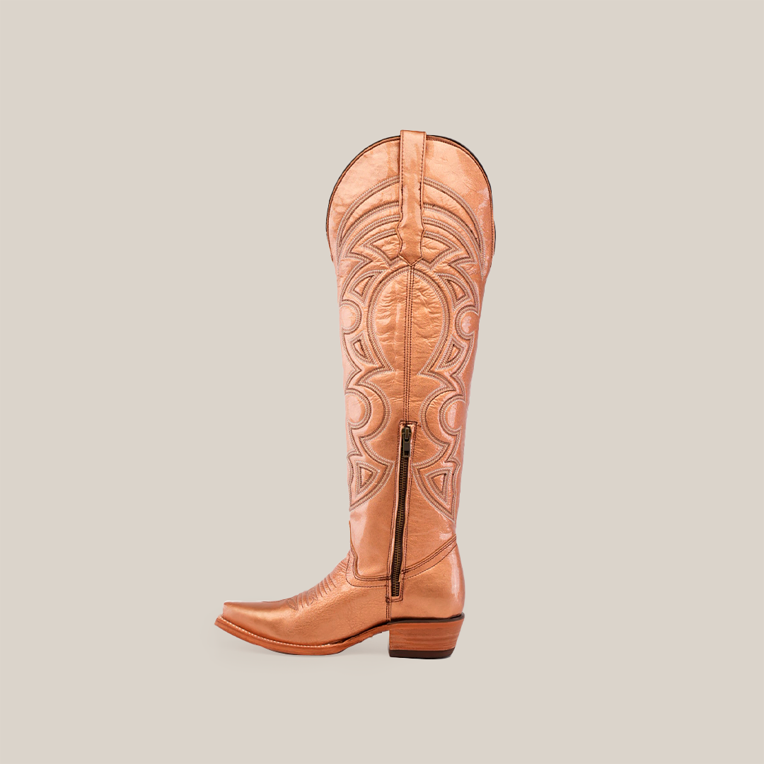 The Taylor Rose Gold knee-high boot, in tan leather, showcases detailed stitching, a side zipper, and a snip toe for an authentic Western style. Its tall shaft and low wooden heel merge classic design with modern flair.