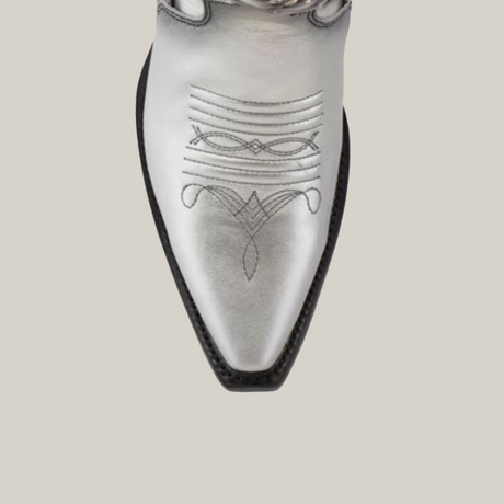 Close-up of the Valentina Silver - Tall Shaft - Snip Toe boot in premium leather, featuring intricate black stitching on the pointed toe. Its sleek design and decorative patterns stand out elegantly against a plain white background.