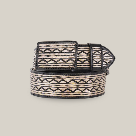 The Artisanal Handmade Silver Belt ZigZag features black zigzag and diamond designs on a beige background. Rolled up with the buckle on top against a white backdrop, its handcrafted beauty is sure to make a statement.