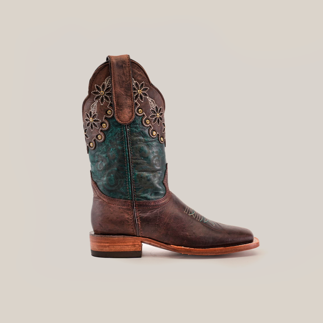 Explore the Grecas Brown - Short Shaft - Square Toe cowboy boot, showcasing intricate floral embroidery on rich brown leather. It features a green lower section with decorative stitching, a flat heel, and pull tabs for easy wear, encapsulating handcrafted luxury western footwear.