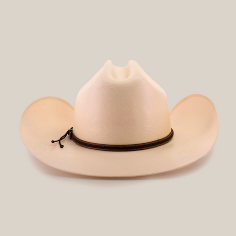 The 1000X Country Straw Hat is a beige cowboy hat, made from high-quality materials, featuring a wide brim and a decorative brown band. The prominent crease on its front adds to its classic charm against the white background.