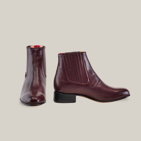 A pair of Napa Wine - Round Toe dark burgundy leather ankle boots with elastic side panels, calidad excepcional, and low heels. One boot is displayed front-facing and the other from the side against a plain white background.