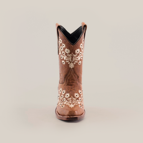 The Abril Studs Orix Snip Toe boot, set against a white background, showcases intricate white floral embroidery on the front and sides of a single brown cowboy boot with a classic snip toe design.