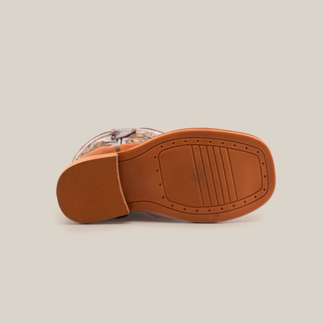 A bottom view of the Cater Honey Square Toe shoe features a rectangular cowhide leather sole with a smooth finish showcasing intricate texture patterns, while the partially visible upper boasts a handcrafted, vibrant design.