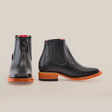 A pair of Napa Black Square Toe Chelsea boots, made from genuine leather with side elastic panels and contrasting tan soles, are displayed on a light background. One boot is positioned forward while the other shows a side view, emphasizing their luxurious craftsmanship.