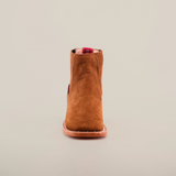 The Prime Suede Caramel Square Toe is a brown suede ankle boot with a square toe and leather sole, centered on a plain white background. Its red pull tab subtly peeks out at the top, adding a splash of color to its classic design.