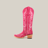 The Amara Pink Suede boot, showcased against a white background, boasts intricate white stitching, a snip toe, medium-height wooden heel, and pull tab on top, embodying classic Western style in profile.