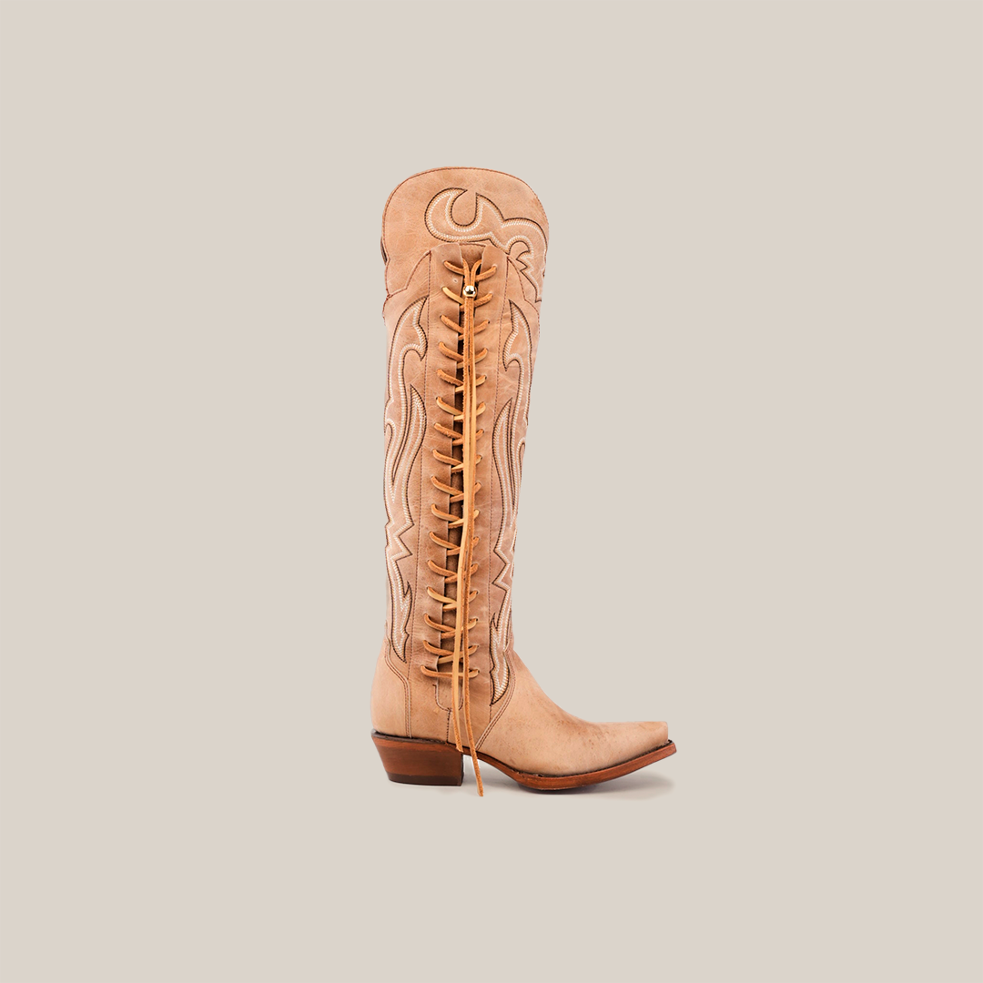 The Tania Orix boot, with its snip toe and low angular heel, is a tan knee-high womens boot featuring intricate embroidery, decorative stitching, and distinctive back laces for a unique design.