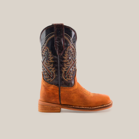 The Cater Honey Square Toe is a cowboy boot made from cowhide leather, with a brown leather foot and an ornate darker stitched shaft. It features classic western styling, low heel, and pull tabs.