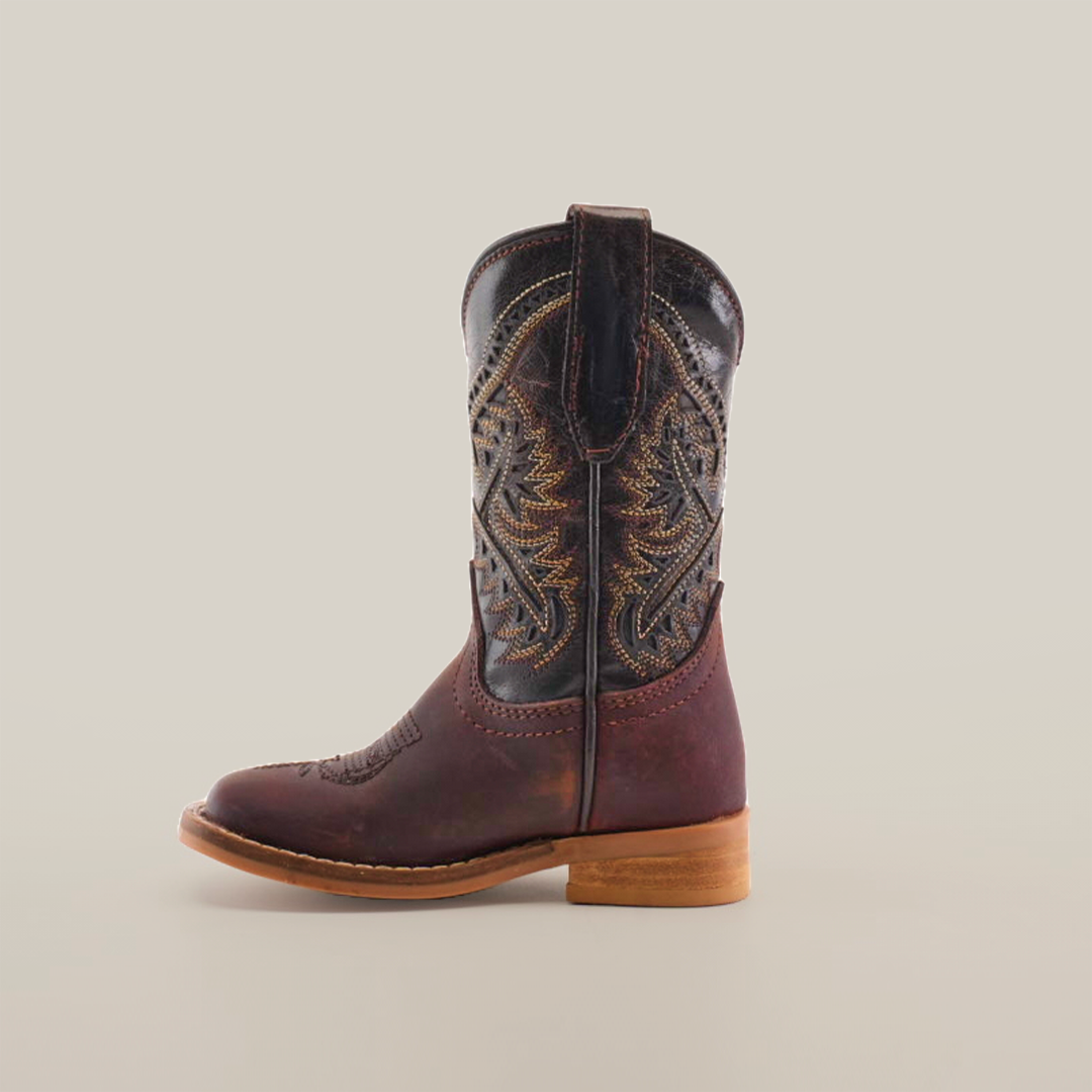 The Salvage Almond Square Toe boot, made from premium cowhide leather, showcases intricate stitching and a rich brown color. It features a low wooden heel, a pull tab at the top, and an elegant square-toe design against a plain white background.