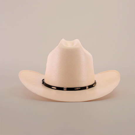 The 500X Dos Carnales Straw Hat is cream-colored with a wide brim and slightly pinched crown, highlighting its quality and durability. It has a black band adorned with decorative gold elements on a plain white background.