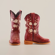 A pair of red cowboy boots, akin to Jatziry Cogñac - Square Toe, is shown on a white background. Adorned with intricate white floral embroidery and wooden soles, one boot is upright while the other leans to the side—ideal for stylish little girls.