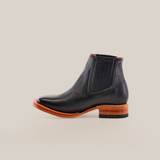 The Napa Black Square Toe Chelsea boot, crafted from genuine leather, features a wooden heel and dark elastic side panels, all showcased against a plain white background.