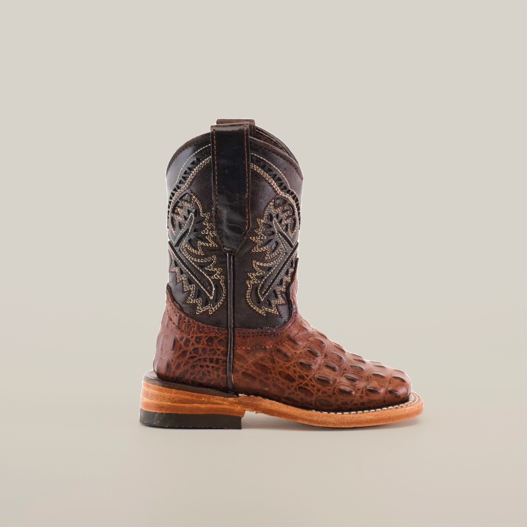 The Caiman Hornback Print Chocolate Square Toe boot features intricate embroidery on its brown leather shaft, textured crocodile-skin-like details below, and a tan leather sole with a low heel, epitomizing classic Western style against a plain white backdrop.