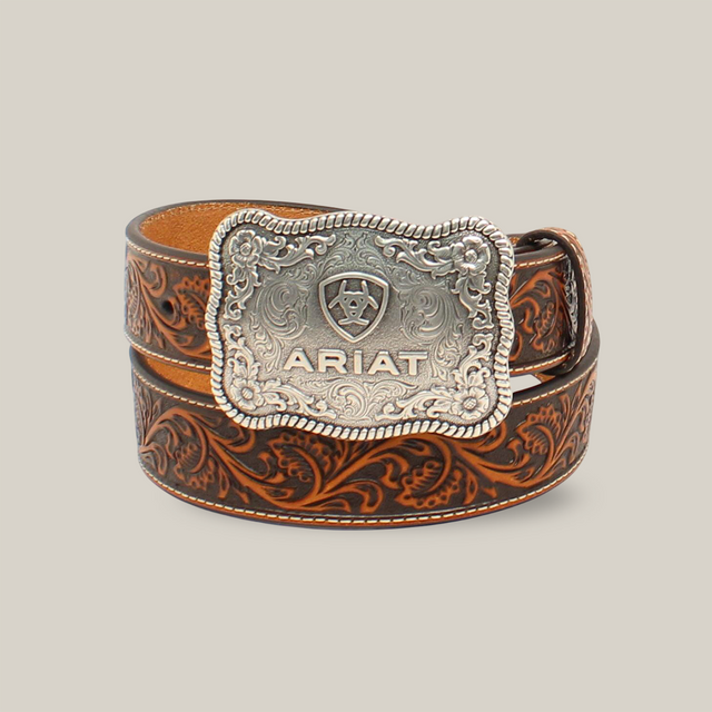 The Ariat Mens Etched Silver Buckle & Brown Genuine Leather Floral Tooled Belt - A1020467 combines rugged elegance with intricate floral patterns and a large, engraved silver buckle, reflecting Western heritage.