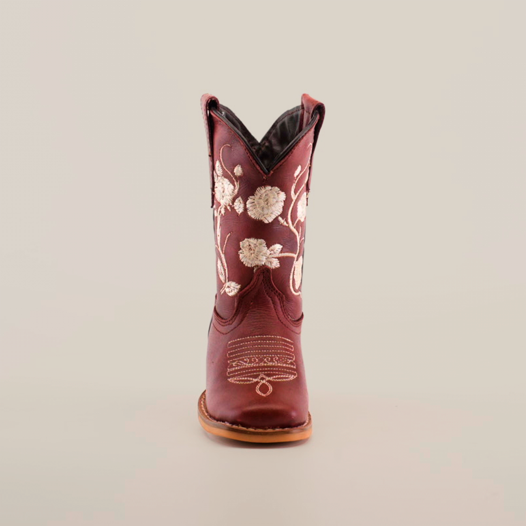 Front view of a single handcrafted leather cowboy boot, akin to the Jatziry Cogñac - Square Toe style, showcasing intricate white floral embroidery on its maroon surface. It features a tan sole and dark interior, set against a white background.