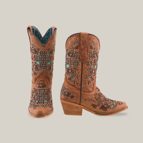 The Alamo Studs Honey -+ Snip Toe boots are girls cowboy boots crafted from brown cowhide leather, featuring intricate floral and cross-shaped embroidery with turquoise stone accents. They have a moderate heel, decorative stitching, and are shown side by side on a white background.