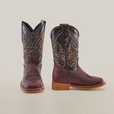 The Salvage Almond Square Toe boots are crafted from premium cowhide leather with intricate shaft patterns. They feature a dark brown color with contrasting light brown soles and stitching, all showcased against a plain white background.