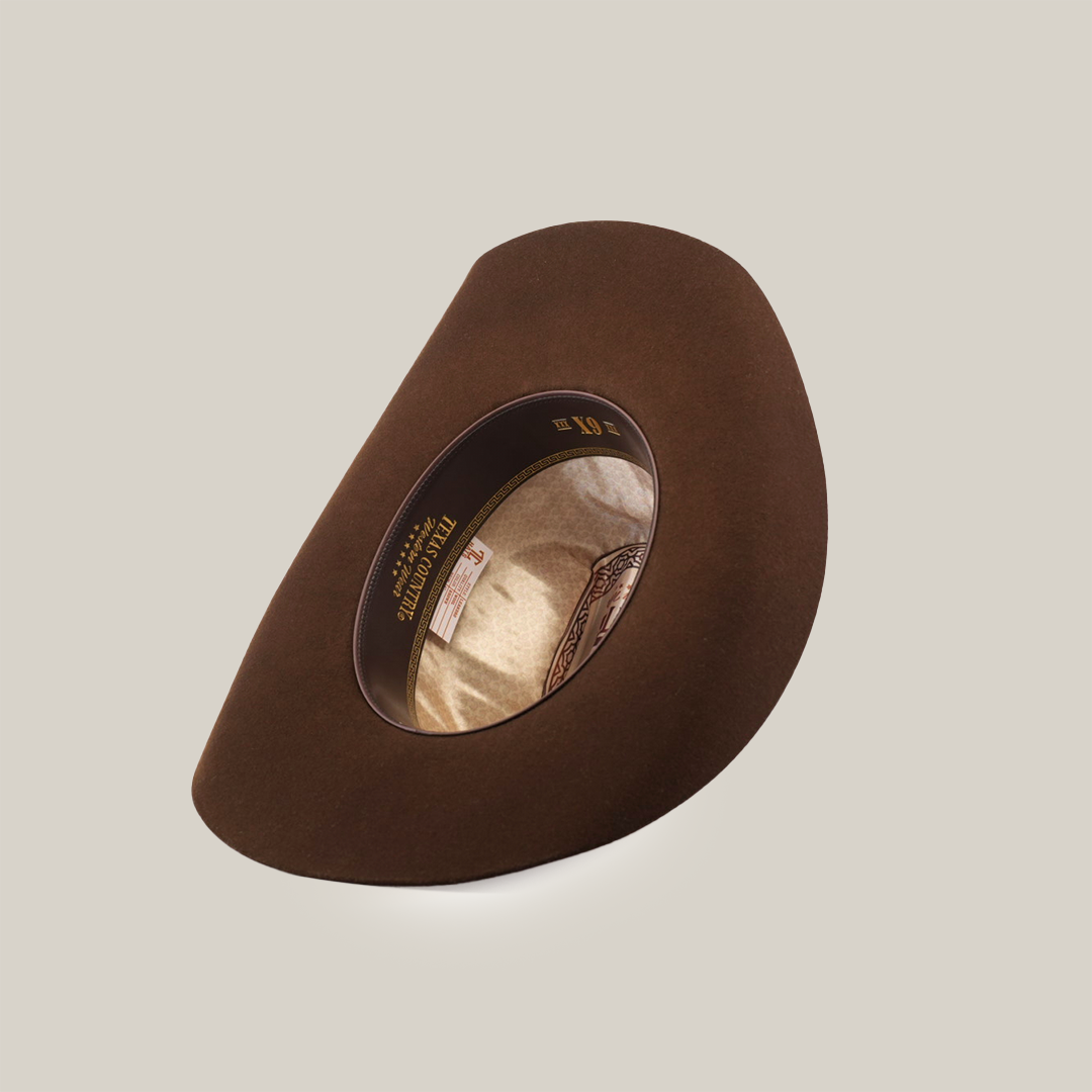 The 6X Leandro Brown Fedora, made from premium sheeps wool, is shown in an angled top view showcasing the inside lining, sweatband with labels, and a slightly upturned wide brim reminiscent of classic designs.