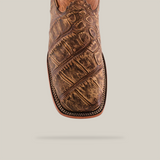 Close-up of the American Alligator Print Rustic Orix Square Toe Boot boasts a detailed brown leather design with a textured elegance and intricate edge stitching, all highlighted by a plain white background.