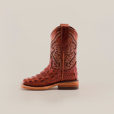 The Caiman Hornback Print Cogñac Square Toe boot stands upright against a white background, showcasing its handcrafted square toe, intricate stitching, premium reptile-patterned leather, wooden heel, and side pull straps.