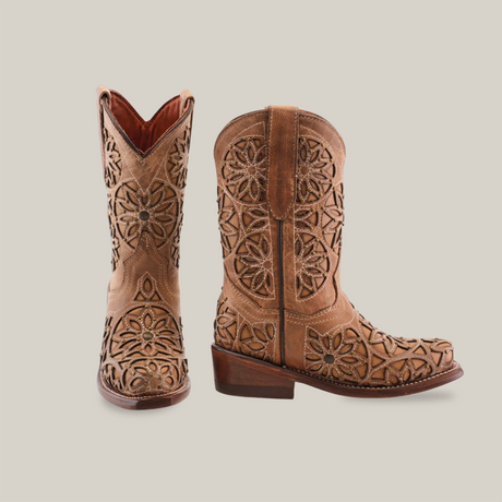 The Vitralli Studs Fawn Snip Toe boots feature intricate floral cutout designs on tan premium leather. One boot faces forward and the other is turned, highlighting the detailed craftsmanship and wooden heels.