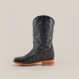 The Caiman Belly Print Black Square Toe cowboy boot features a black design with a striking Caiman Belly Print and decorative shaft stitching. It has a wooden sole and low heel, ideal for cowboy enthusiasts, set against a plain white background.