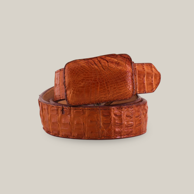 The Exotic Full Quilt Caiman - Brandy Belt features a large, textured buckle with a distinct crocodile skin pattern, coiled elegantly on a plain white background, exemplifying exquisite exotic leather craftsmanship.