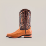 Meet the Cater Honey - Slip Resistant Sole - Rodeo Toe boot: a single cowboy boot with intricate embroidery, made from premium cowhide leather in tan and dark brown, set on a wooden heel against a plain white background.