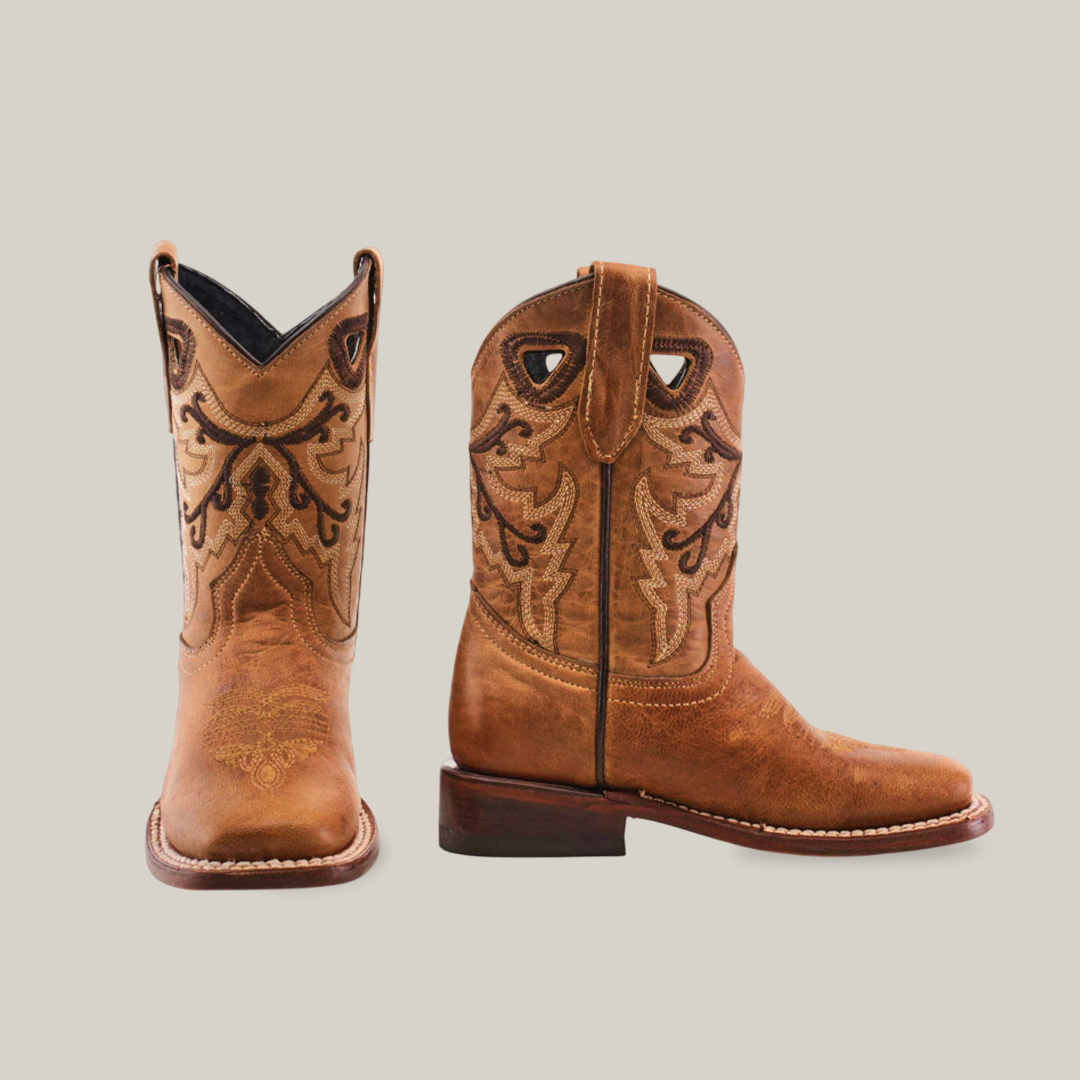 A pair of Matcat Fawn - Square Toe boots highlights expert craftsmanship with premium leather, intricate dark brown embroidery on brown cowboy boots, a slightly pointed toe, and detailed views of one boot upright and the other showing the heel and sole on a plain white background.