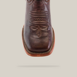 Close-up view of the Dessert Camel - Square Toe cowboy boot in premium brown cowhide. It features intricate vamp stitching, a visible leather sole, and detailed edge stitching, all set against a plain white background. This boot epitomizes timeless elegance.