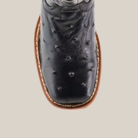 Close-up top view of the Karoo Ostrich Print Black Square Toe cowboy boot in premium cowhide leather, featuring unique textured patterns. The boot boasts a square toe, brown sole with white stitching, and an embossed design on the upper part.