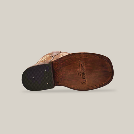 The image displays the sole of the Margacruz Studs Orix - Square Toe cowboy boot on its side. The brown sole, with textured rubber on the heel and metal rivets, shows the Texas Country brand name. Crafted from premium leather, it lies against a plain white backdrop.