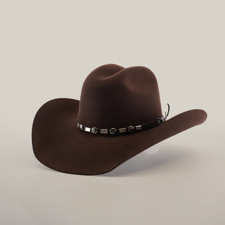 The 6X Chihuahua Brown Western hat, featuring a wide brim and a decorative leather band with metal accents, rests on a white surface, showcasing its classic charm.