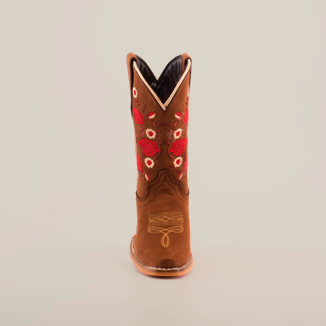 The Mia Copper Suede - Snip Toe boots feature premium leather in a brown cowboy design, complemented by red and white floral embroidery on the shaft. Ankle stitching enhances the look, and a light-colored sole completes the design against a plain white backdrop.