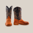 Showcasing a side and front view, the Cater Honey Square Toe boots are handcrafted with brown cowhide leather feet and dark shafts featuring intricate stitching. With rounded toes, stacked heels, and pull straps on the sides, these boots exude classic Western charm.