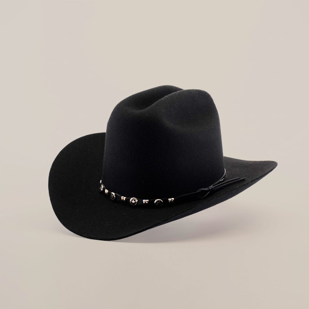 The X 2 Carnales Black is a black felt cowboy hat with a wide brim crafted from sheep wool. It features a decorative band with small metallic accents against a plain white background.