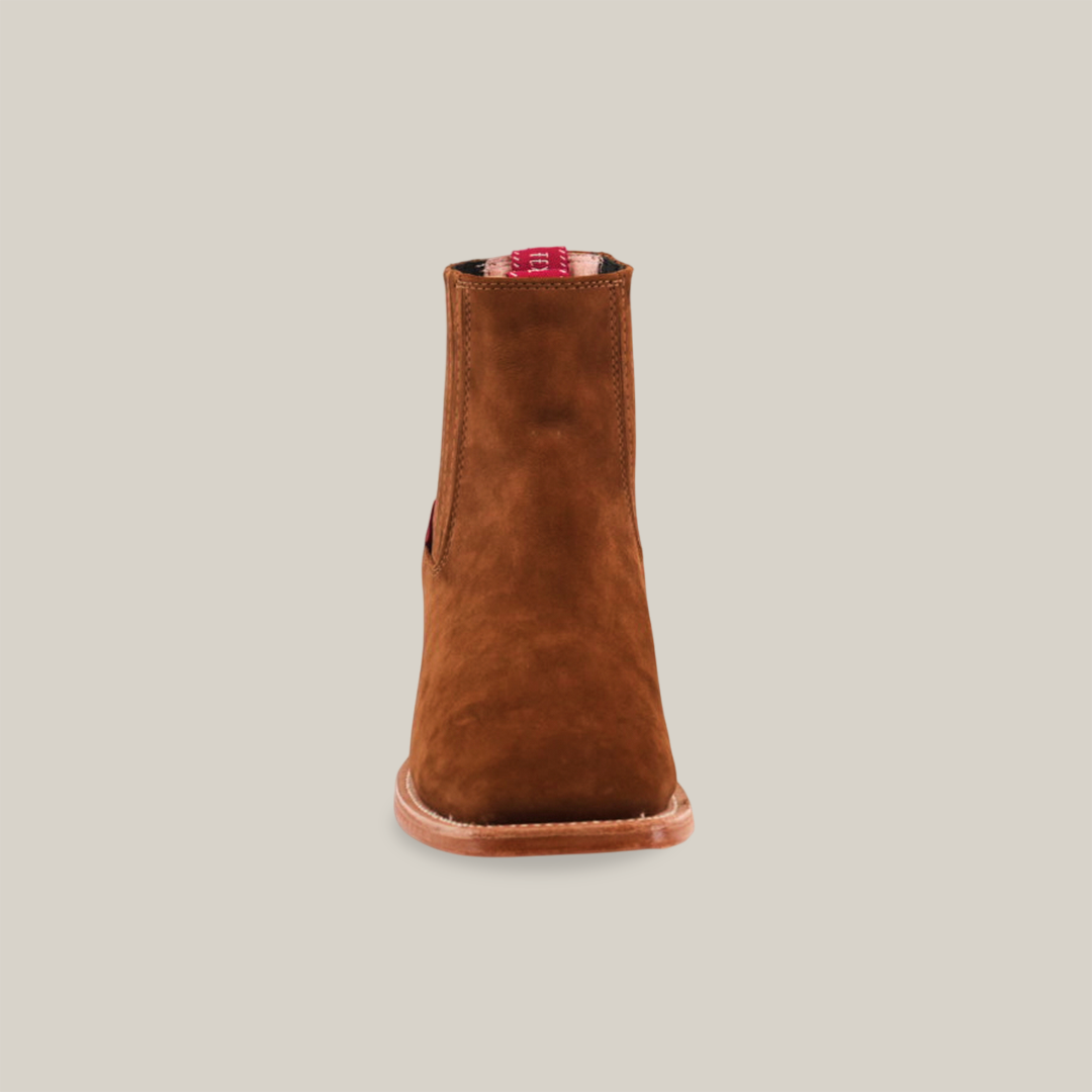 The Prime Suede Caramel Square Toe features a single brown suede ankle boot with a smooth finish. Viewed frontally, it boasts a rounded toe and light brown sole, embodying Western style against a plain white background.