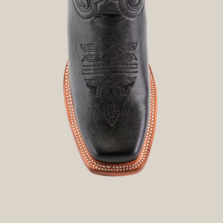 Close-up of a Western Stitch Black Lustre boot, highlighting intricate toe stitching. Made from premium leather, it features a narrow square toe and brown sole with white edge stitching, set against a plain white background.