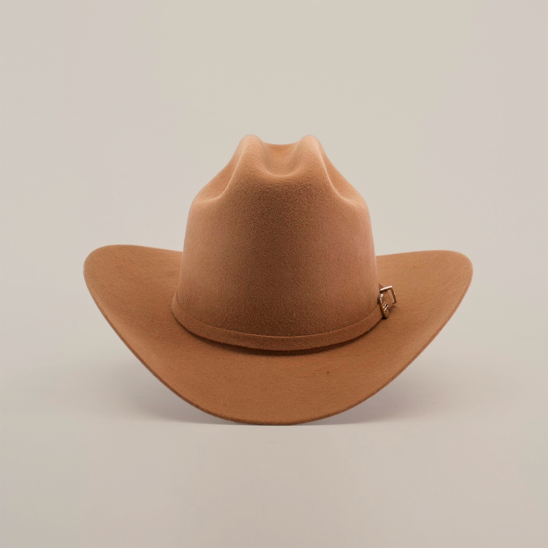 The 6X 2 Carnales Fawn is a classic brown cowboy hat made from sheep wool, with a wide brim and decorative band featuring a small metal buckle. Set against a plain white background, this quintessential western headwear is perfect for any adventurer.