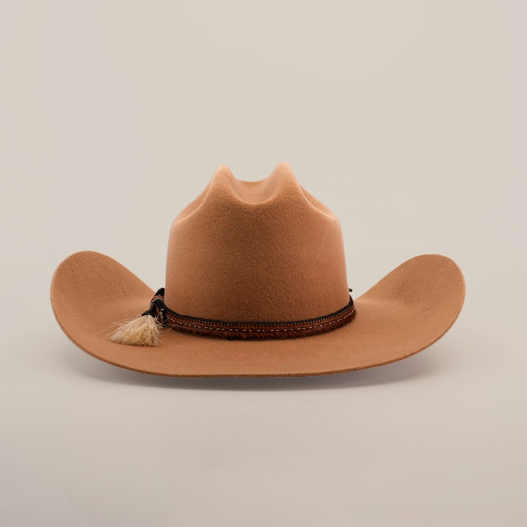 The 6X Doble SS Fawn, a sheeps wool cowboy hat in brown, features a wide brim and decorative leather band with a small tassel, set against a plain white background.