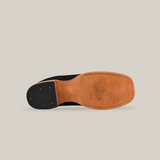 The image displays the sole of the Prime Suede Black - Square Toe shoe, featuring a natural tan color. The western footwear showcases a logo and text etched into premium materials, with a heel that has darker patches and small embedded nails against a plain white background.