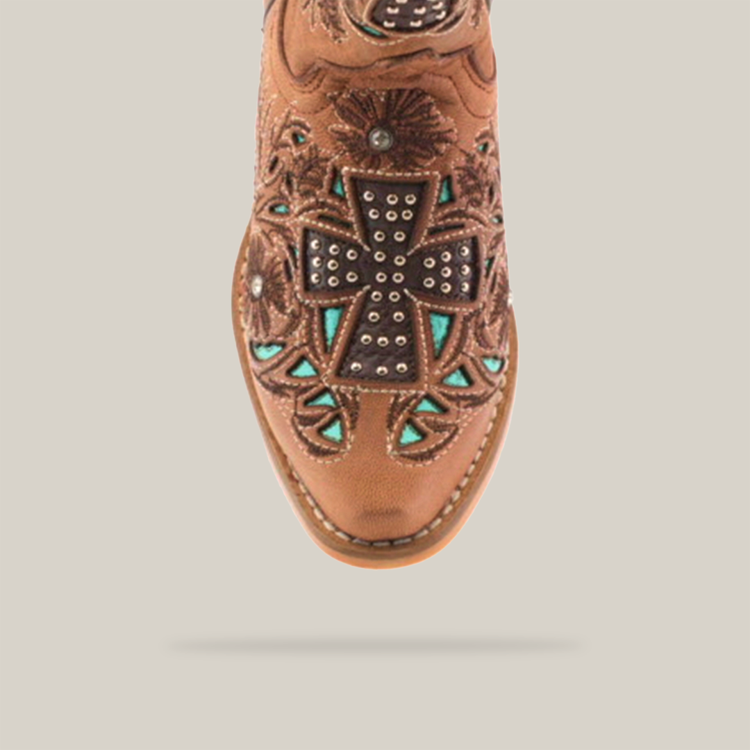 Close-up of the toe of an Alamo Studs Honey - Snip Toe cowboy boot in brown cowhide leather, featuring intricate floral stitching and a large studded cross with turquoise accents. These boots are perfect for anyone seeking standout girls footwear with detailed embellishments.