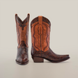 A pair of Handtooled Flowers Brown boots highlights premium leather with intricate stitching and patterns. One boot stands upright, while the other leans slightly against a plain white background, embodying handcrafted elegance.