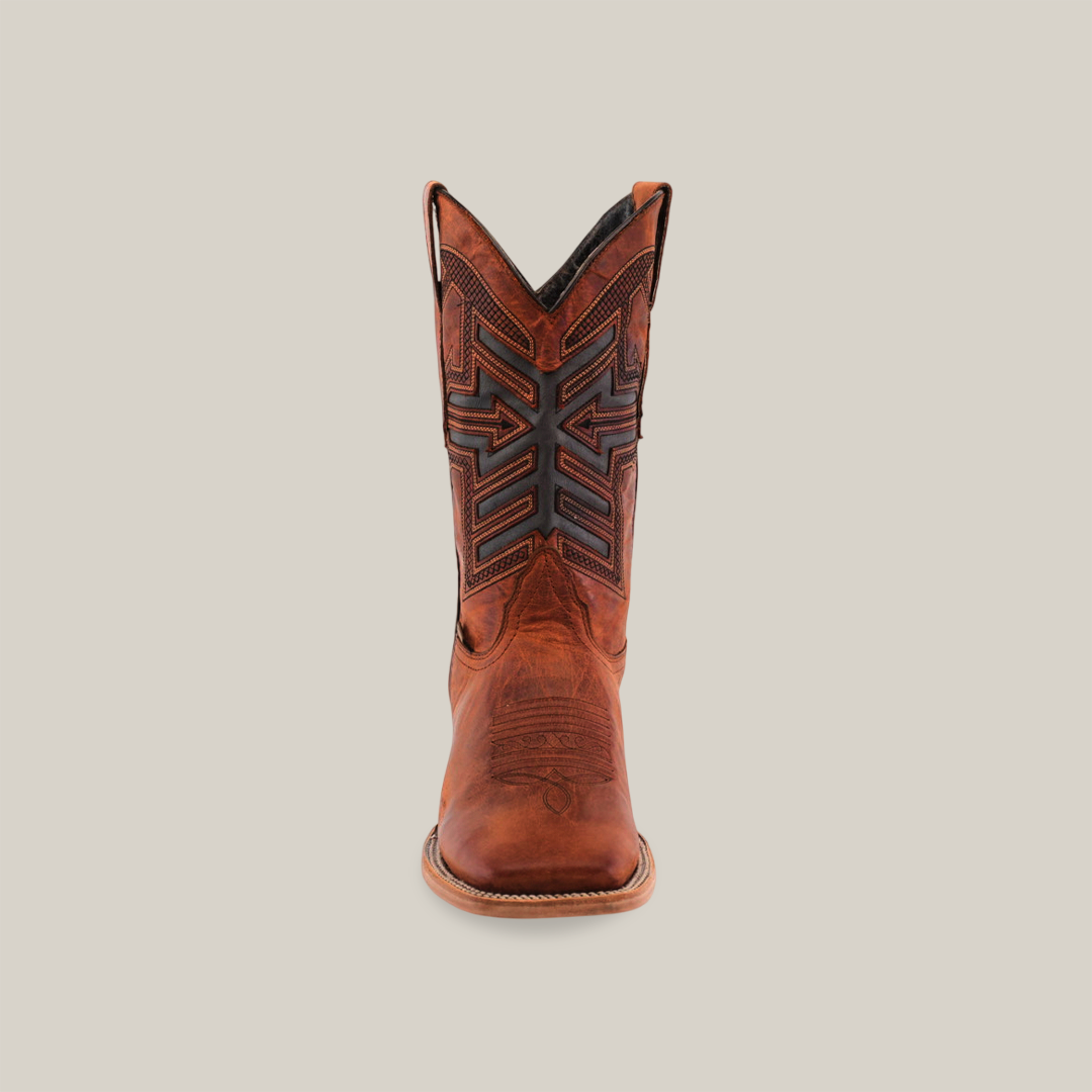 The Rustic Cogñac - Square Toe, a single brown cowboy boot, is meticulously handcrafted from premium cowhide leather with intricate black stitching and patterns. Against a plain white background, it features a pointed toe and high shaft for a striking look.