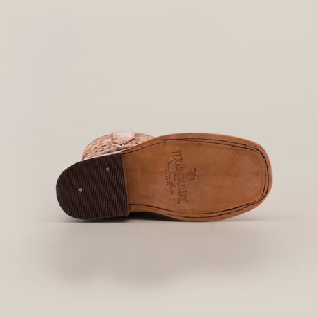 The image shows the sole of the Handtooled Leave Brown Square Toe shoe, made from premium cowhide leather. It features a textured heel and smooth leather forefoot with embossed text and logo on this Western-style piece, appearing upside down.