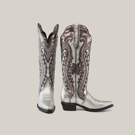 A pair of handcrafted Valentina Silver - Tall Shaft - Snip Toe cowboy boots in metallic silver and bronze, featuring intricate swirling patterns. One boot stands upright, the other angled to highlight the pointed toe and low heel against a light gray background.